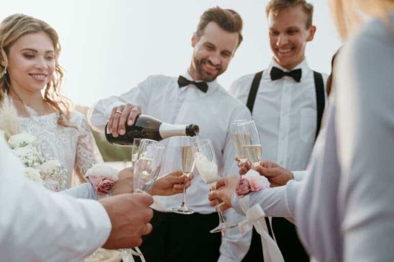 robe mariée blanche dentelle marié noeud papillon noir sert le champagne extérieur vin d'honneur