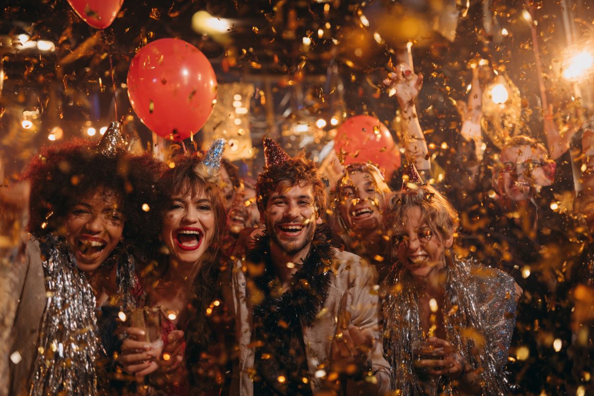 Groupe d'amis avec accessoires devant un photobooth pendant une soirée d'anniversaire