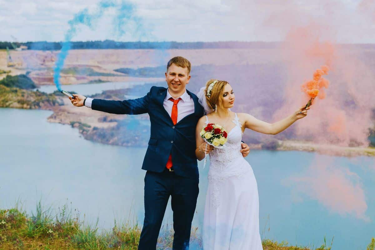 séance photographie mariage couple des mariés costume et robe blanche fumigène bleu et orange dans leur main