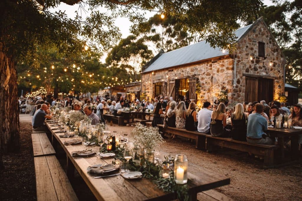 Buffet de mariage champêtre style grazing table, présenté sur des tonneaux et caisses en bois avec fromages, charcuteries et décorations végétales