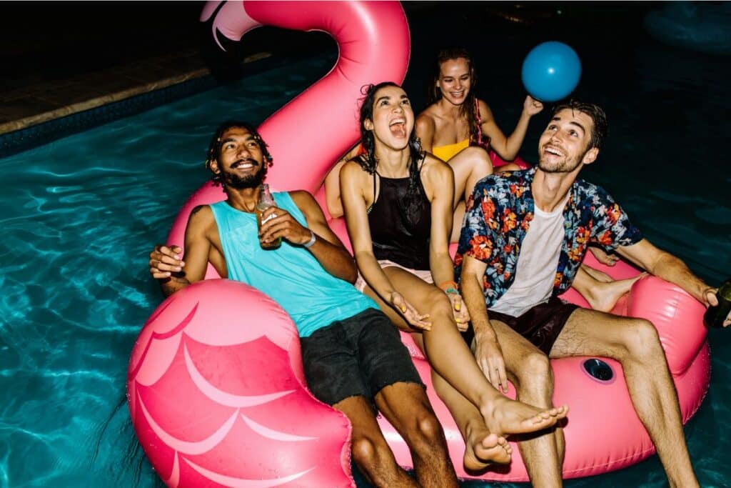 fête pool party flamand rose bouée gonflable invités dans la piscine nuit soirée