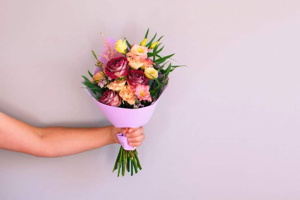 homme avec bras uniquement qui offre un bouquet de fleurs fraiches et colorés
