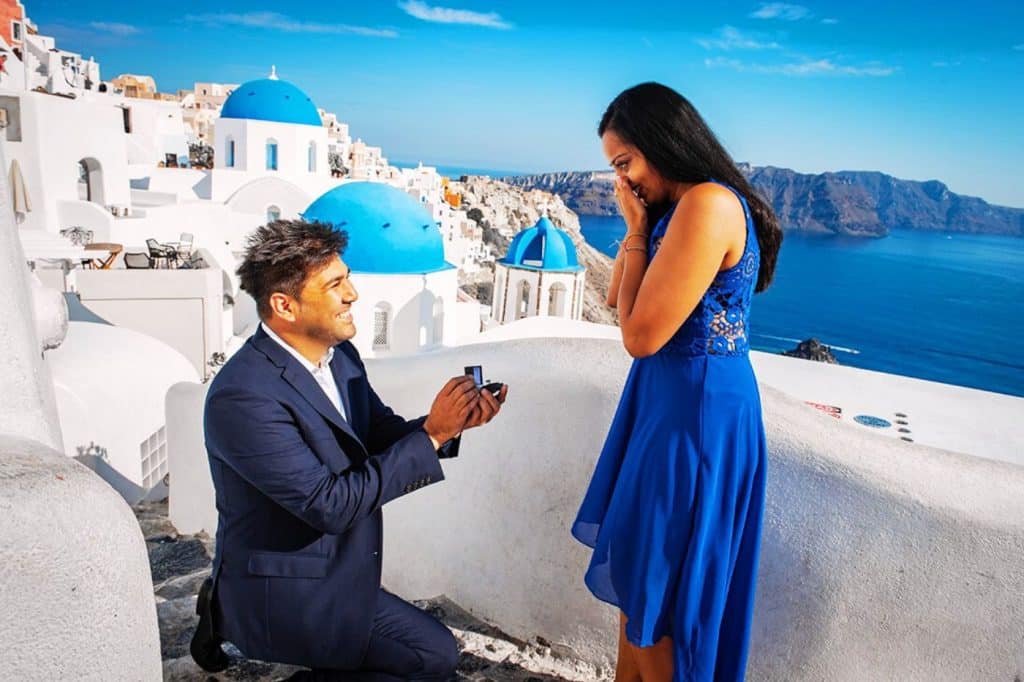 homme demande sa femme en mariage à genoux toit santorin grece