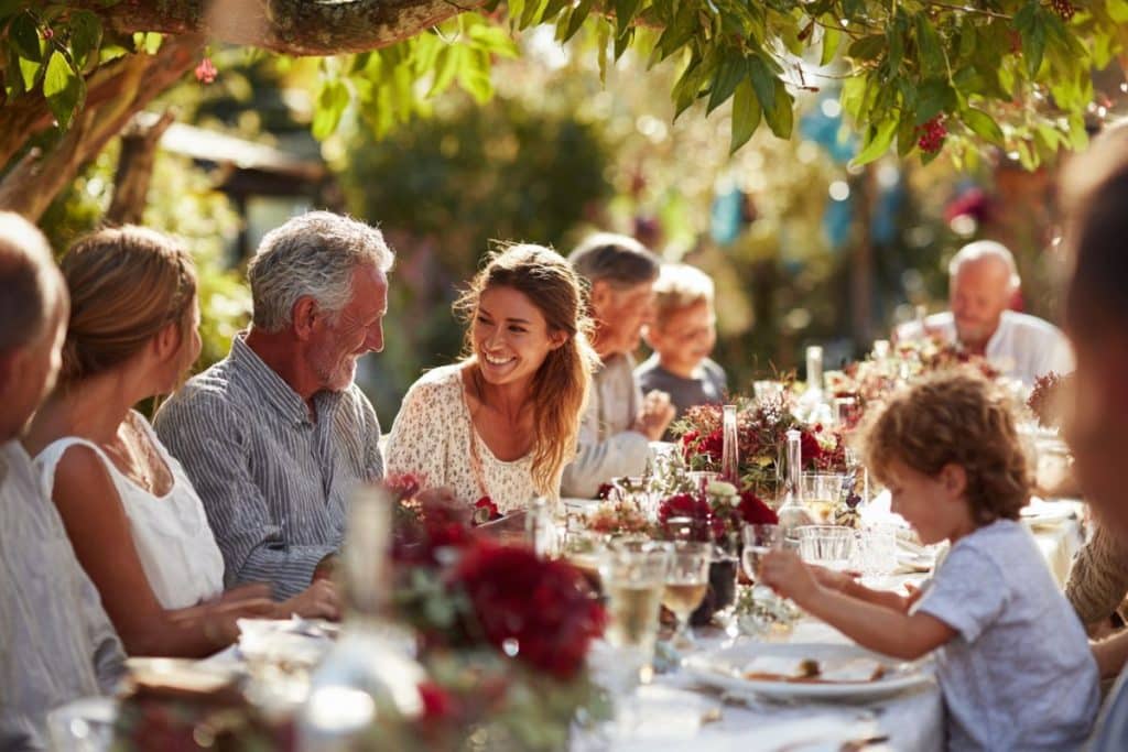 Grande fête de famille en extérieur avec décoration rouge rubis, réunissant enfants et petits-enfants autour du couple fêtant ses 35 ans de mariage.