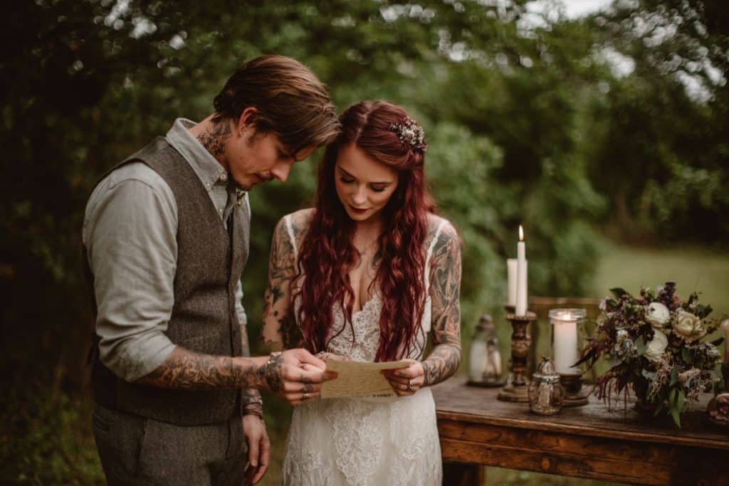 Un couple lit ses vœux de mariage dans un décor champêtre pendant une cérémonie symbolique