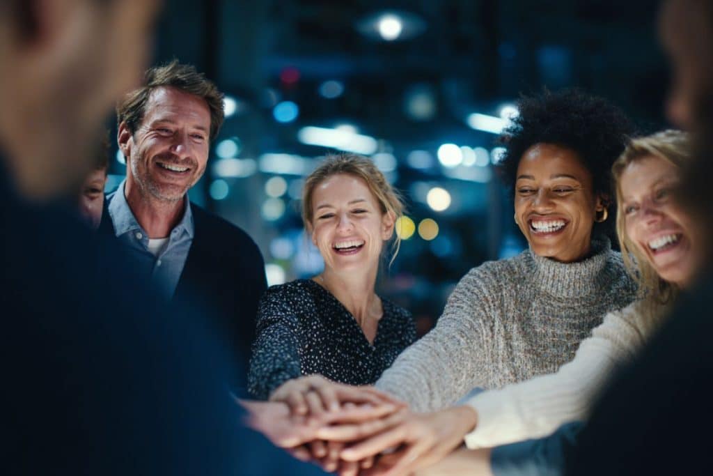 Activité de team building en soirée d’entreprise avec une équipe en cercle qui se serre les mains et sourit