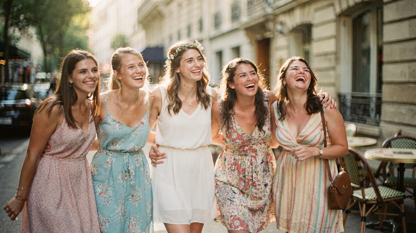 Groupe de copines et future mariee riant dans une rue parisienne pendant un EVJF