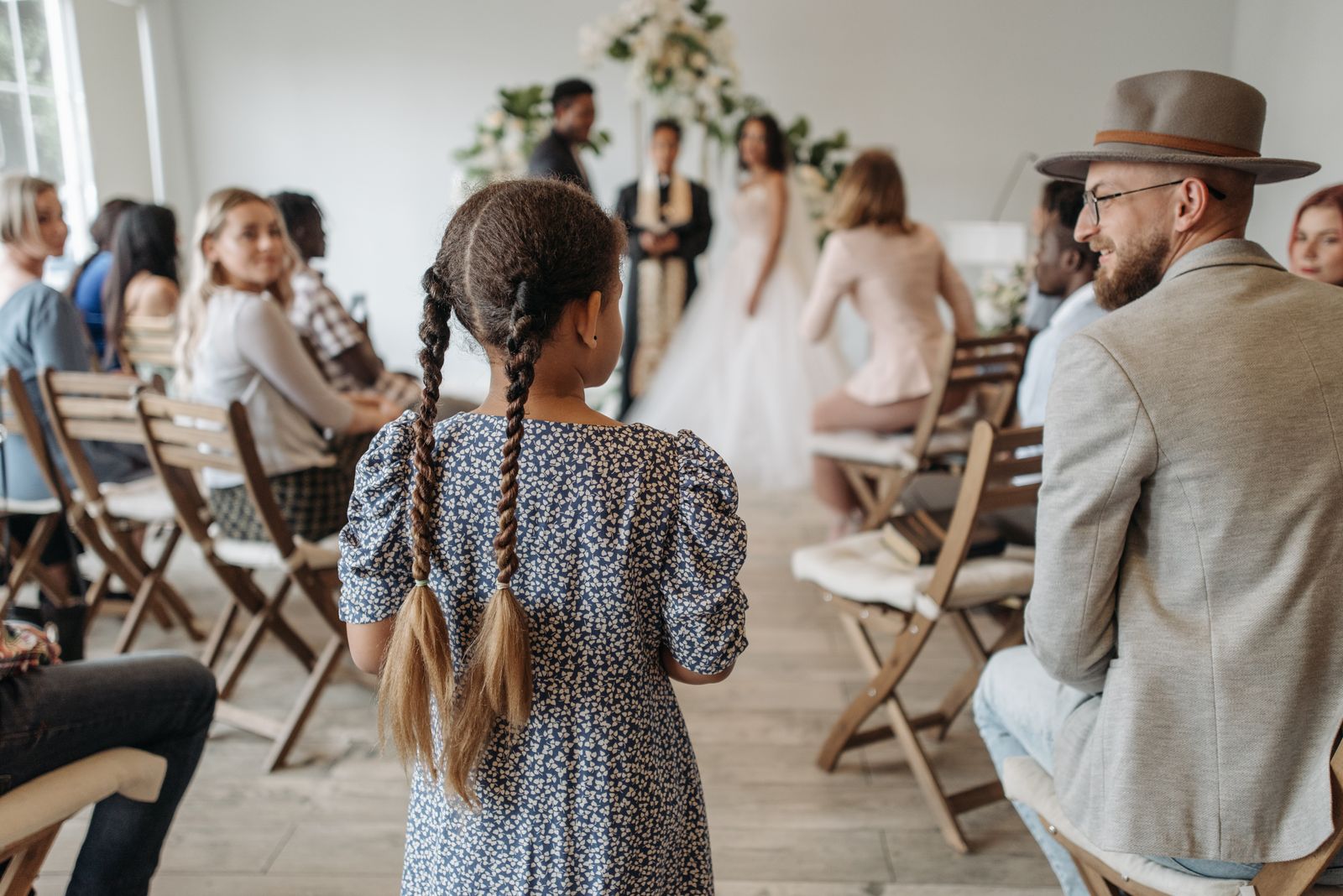 Invités assis pendant une cérémonie de mariage, une fillette aux tresses de dos dans l'allée